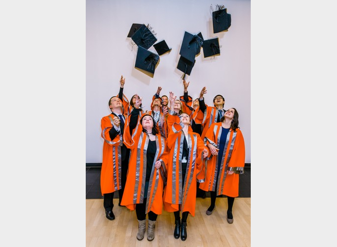 A group shot of all of the graduate throwing their motarboards into the air.
