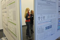 Two female students looking at the poster wall and smiling