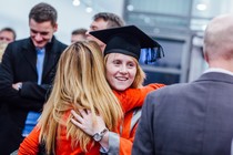 Janna Aarse hugging someone, smiling and wearing her mortar board