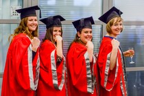 Four female graduates facing the camera side on, with raised fists