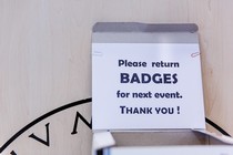 A sign which reads 'Please return BADGES for next event'