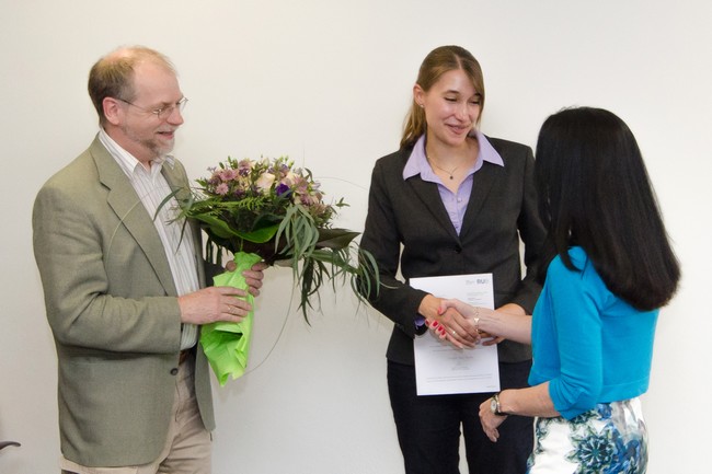 Michael Hollmann holding a bunch of flowers watching Veronika shake hands with Denise manahan-Vaughan