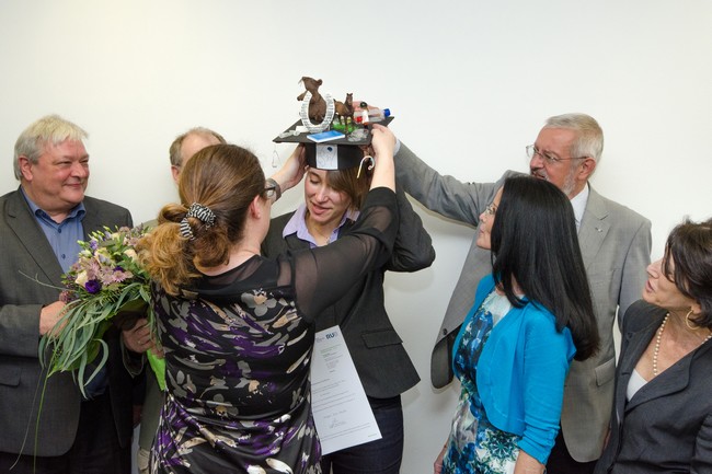 Ulf Eysel placing a 'PhD hat' on Veronika's head whilst various PhD Commission members look on
