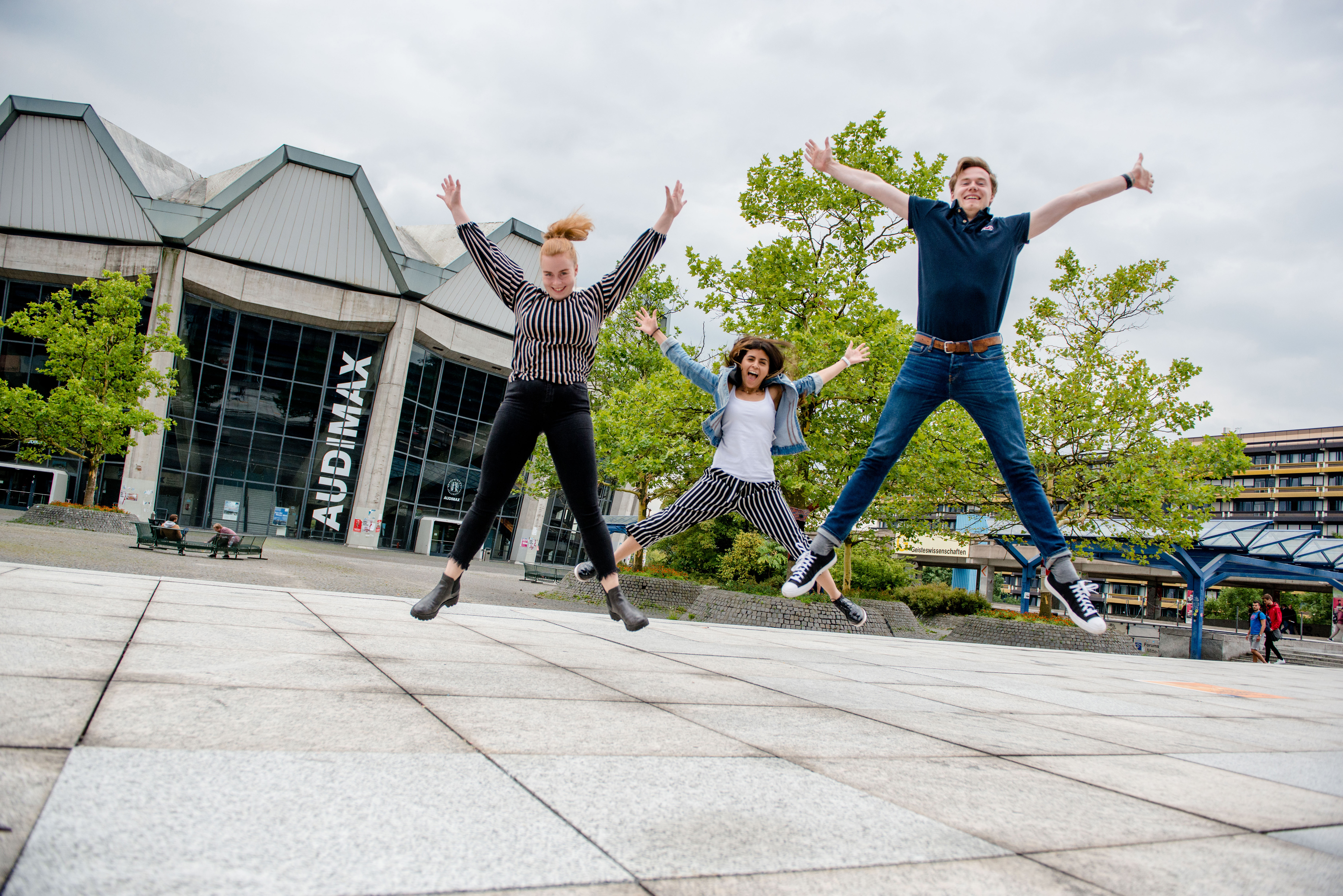 Drei Studierende springen auf dem Forum der RUB in die Höhe