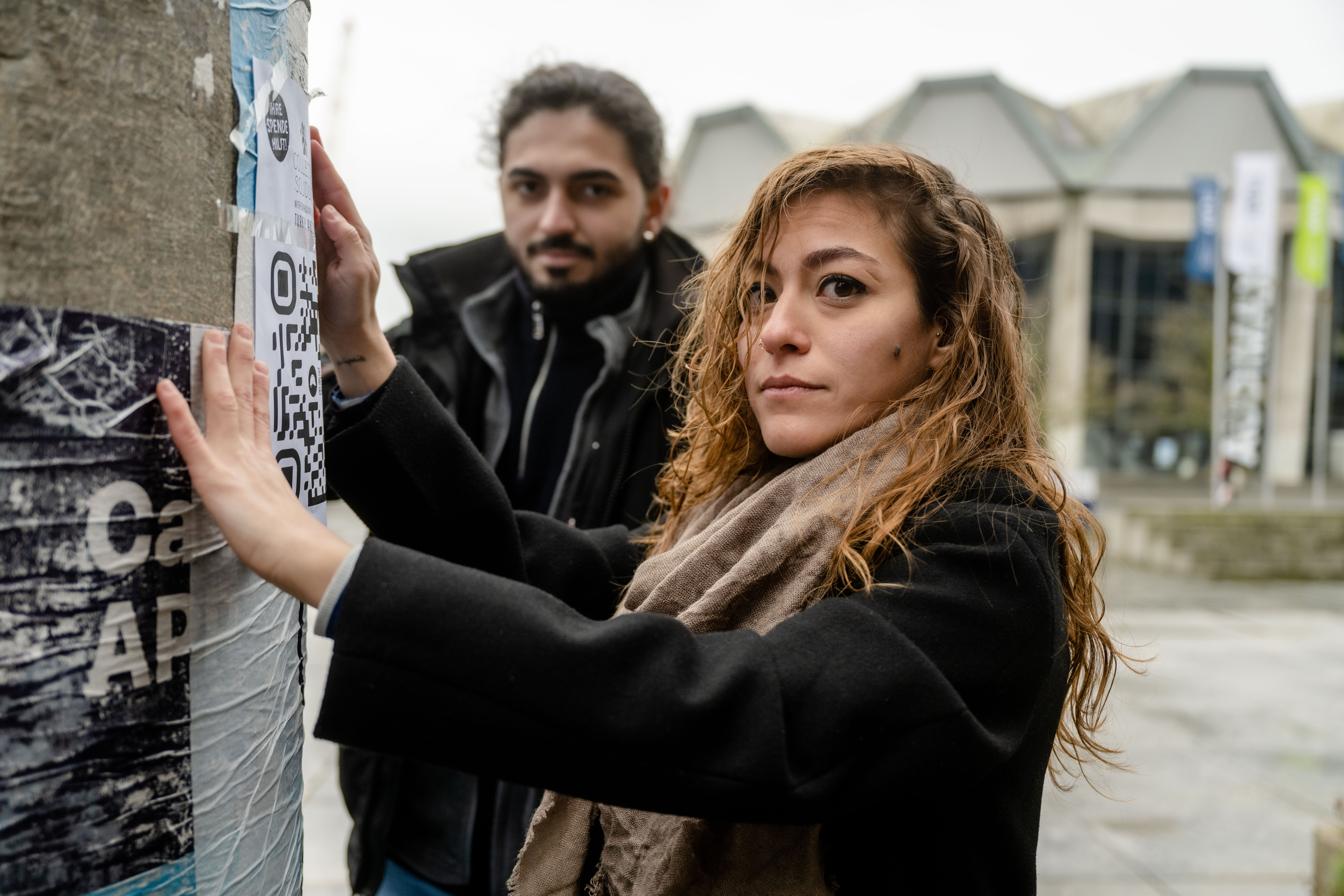 Studentin Sena Demir beim Plakatieren auf dem Campus.
