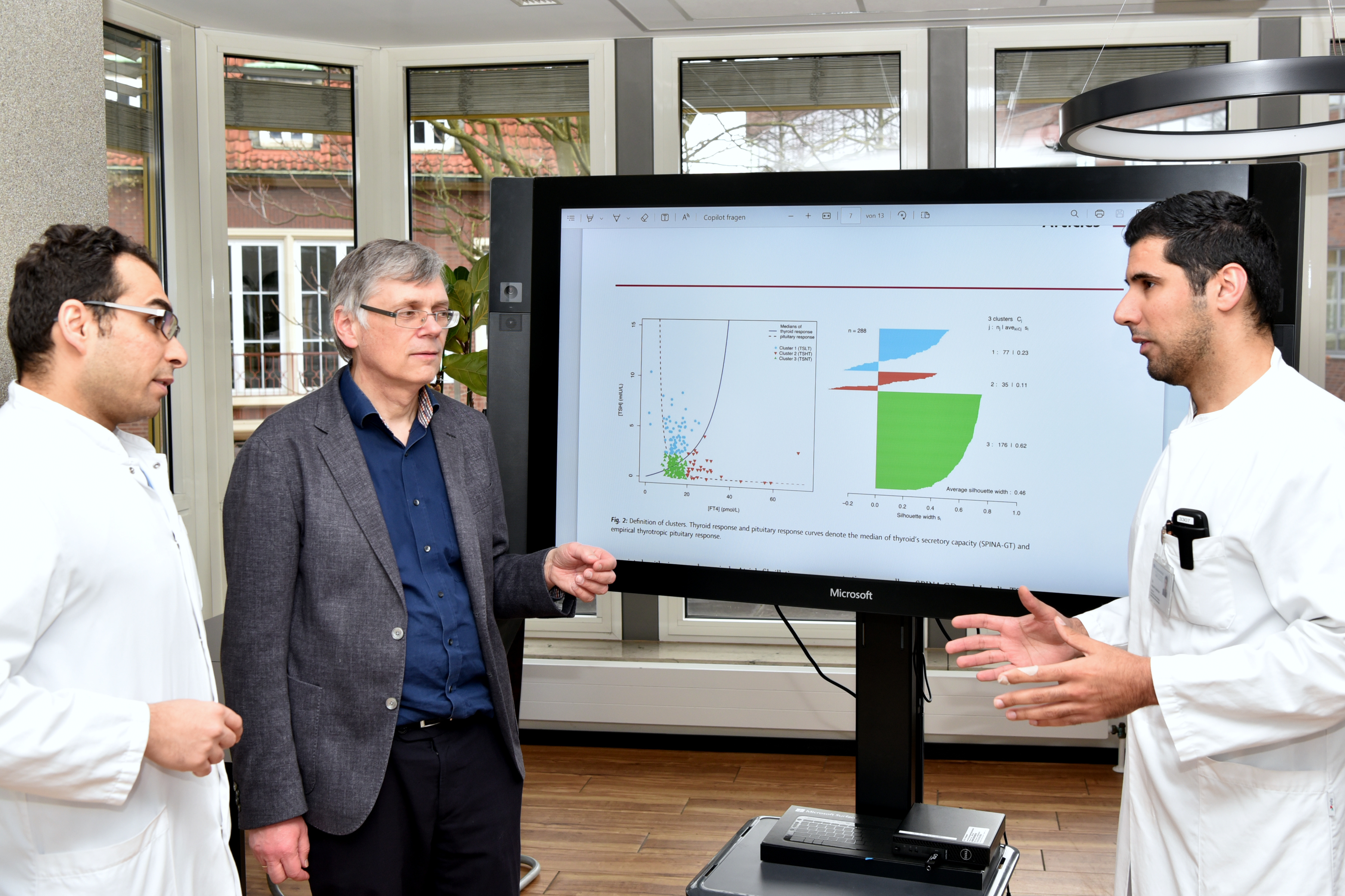 Drei Forscher stehen vor einem Monitor