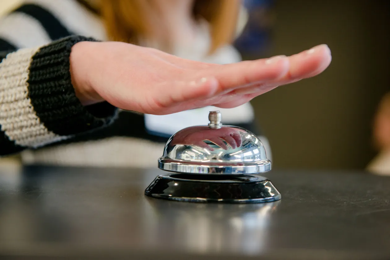 Hand über Klingel an einer Rezeption 