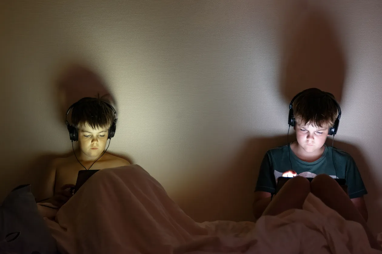 Zwei Kinder im Bett mit iPads