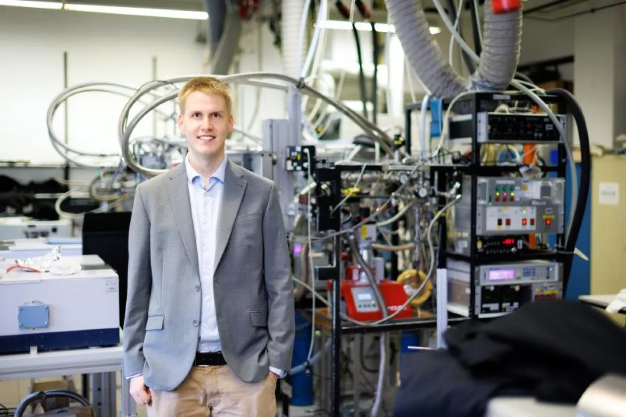 Ein Mann im grauen Jackett steht vor einer Laboranlage