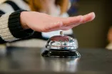 Hand über Klingel an einer Rezeption 