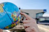 Jemand zeigt mit dem Finger auf einen Globus