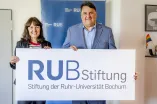 Eine Frau und ein Mann präsentieren ein Banner, auf dem RUB Stiftung steht