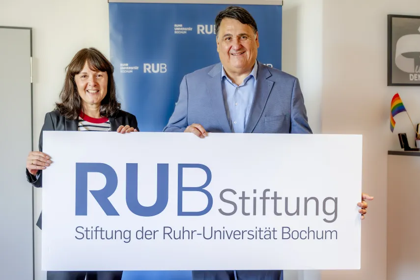 Eine Frau und ein Mann präsentieren ein Banner, auf dem RUB Stiftung steht