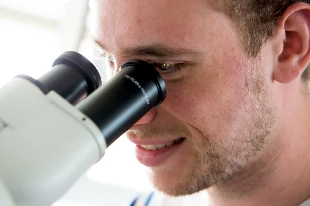 Junger Mann schaut in ein Mikroskop